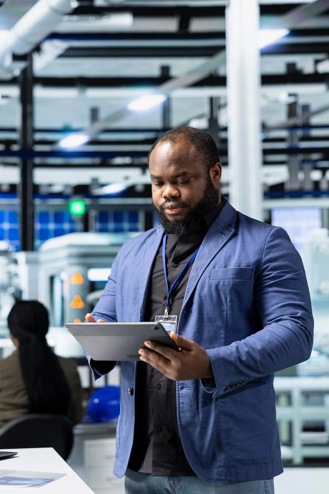 An African American businessperson walks through a modern factory.